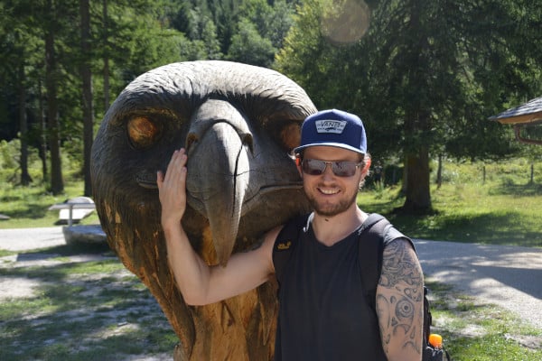 John standing by a wooden eagle's head in the Berchtesgaden Nationalpark